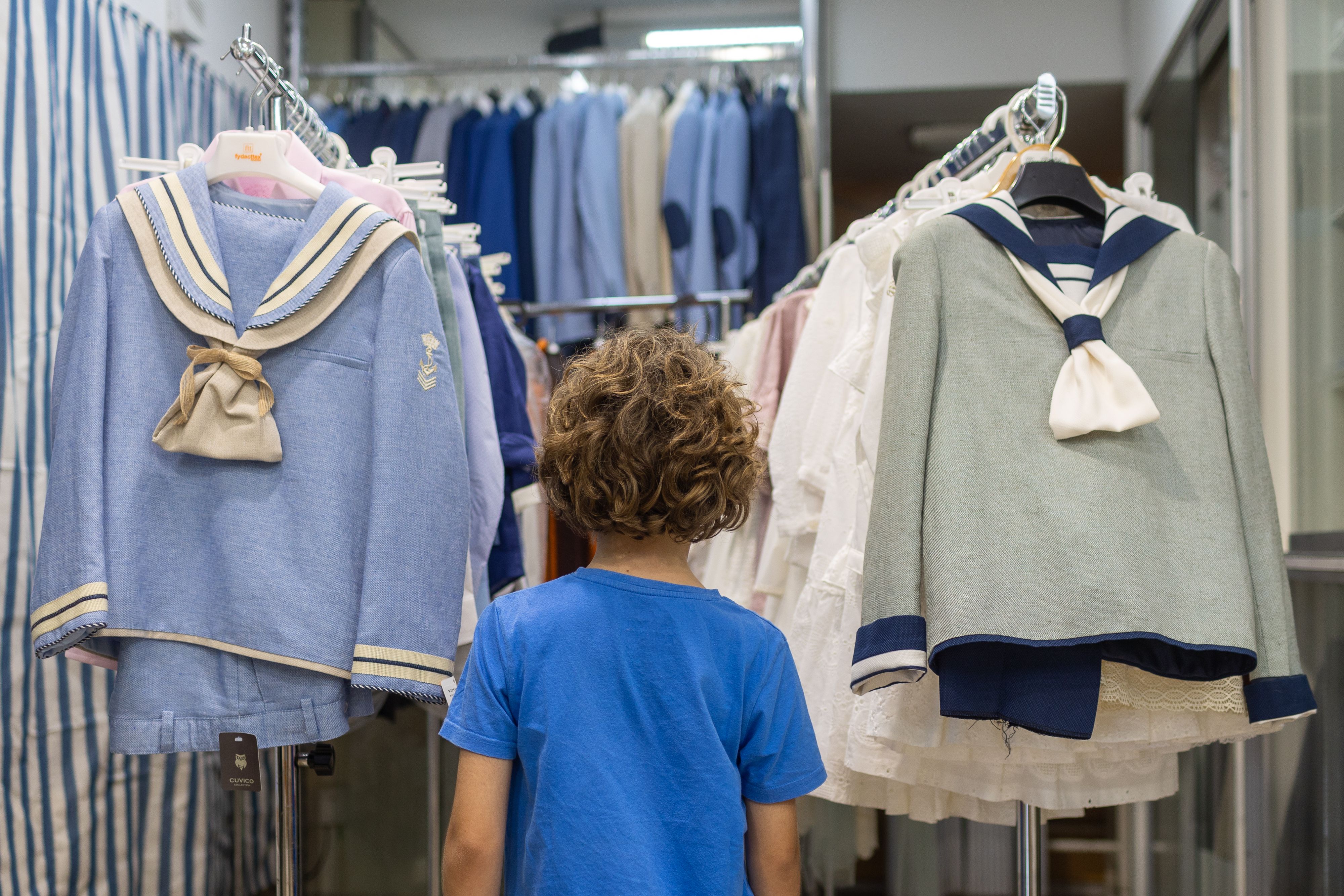 Un pequeño, delante de trajes de comunión.
