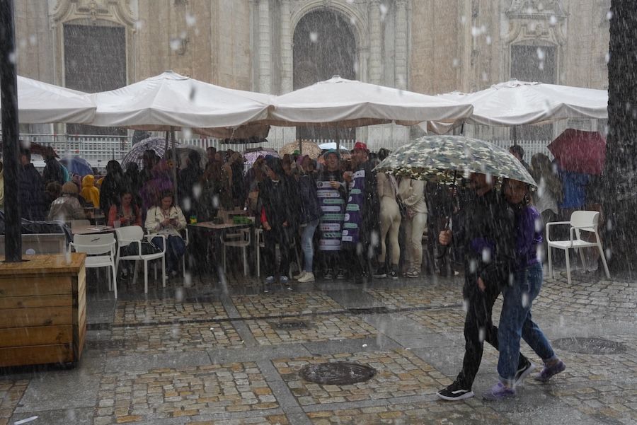 Personas refugiándose del chaparrón, a mediodía de este domingo en Cádiz.